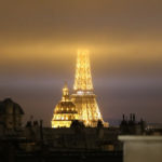 The Eiffel Tower with its top in the clouds and the dome of the Invalides