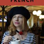 woman wearing a beret and a striped sailor shirt looking stereotypically French and drinking a cup of coffee