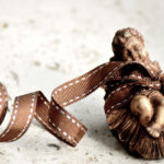 Chrismas decoration of the baby Jesus with a brown ribbon wrapped around it