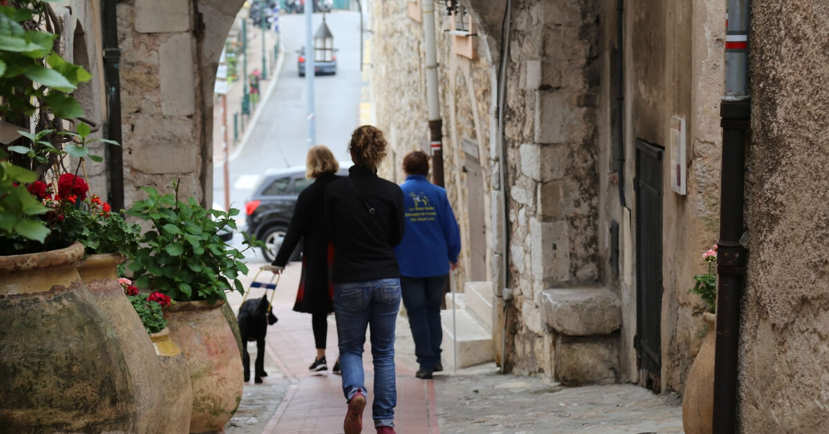 A womand and her guide dog walking through the streets of La Turbie in Provence