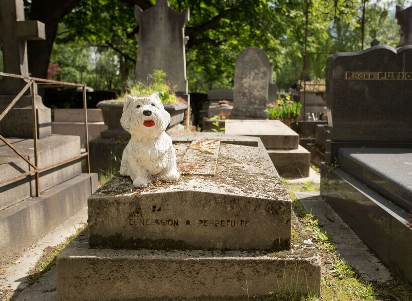 grave with a scotty dog statue on it at pere lachaise cemetery