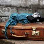 vintage suitcase with blue scarf and old camera on top