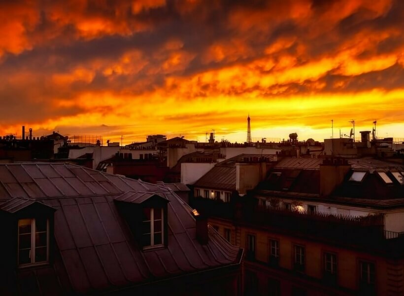 paris rooftops with red and yellow sky; secrets to finding an apartment in paris