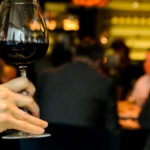 person holding a glass of red wine to smell it during a wine tasting