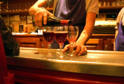 waiter serving 3 glasses of red wine at a bar