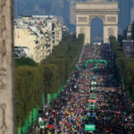 crowd of runners at the paris marathon between the arc de triomphe and place de la concorde
