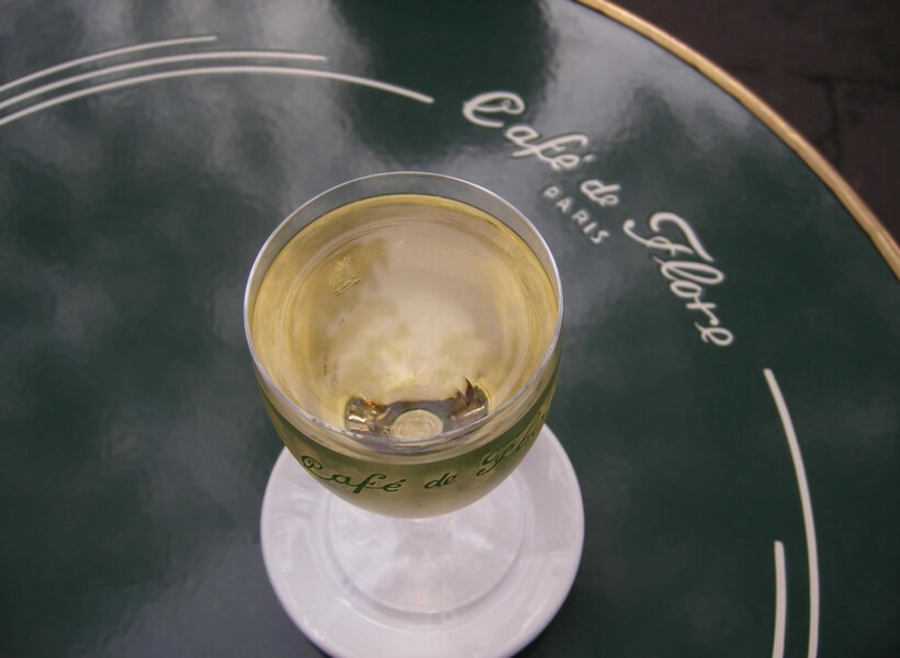 glass of white wine on a café de flore tray; first time in paris