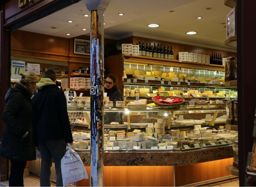 cheese store in paris, two women customers selecting the products they want and a woman clerk helping them