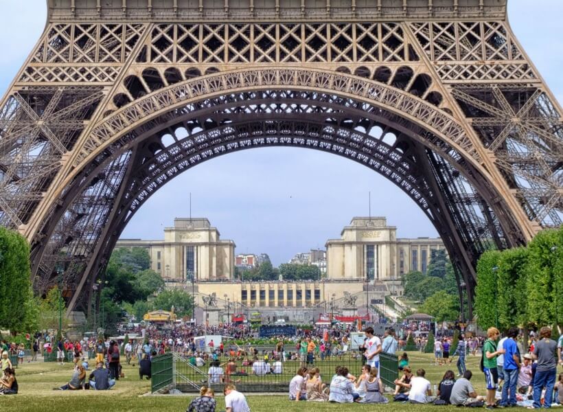 many people sitting under the eiffel tower and enjoying the nice weather