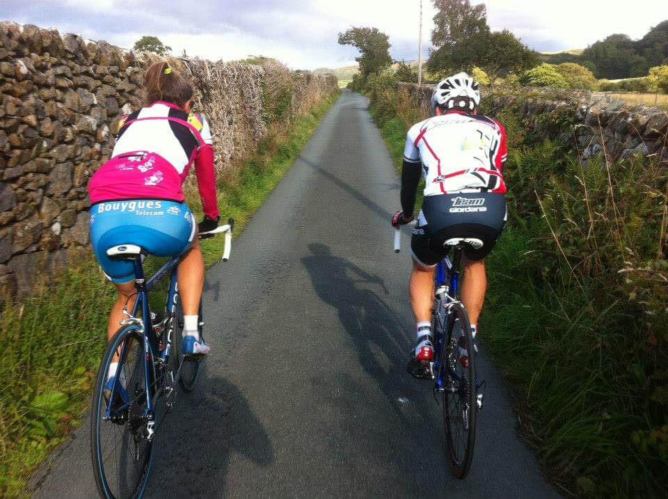 one female and one male cyclists riding on a scenic narrow french road