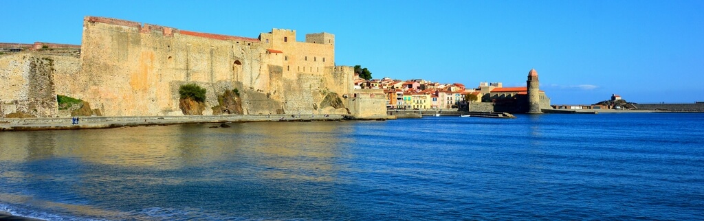 collioure beach, blue water, town in the background