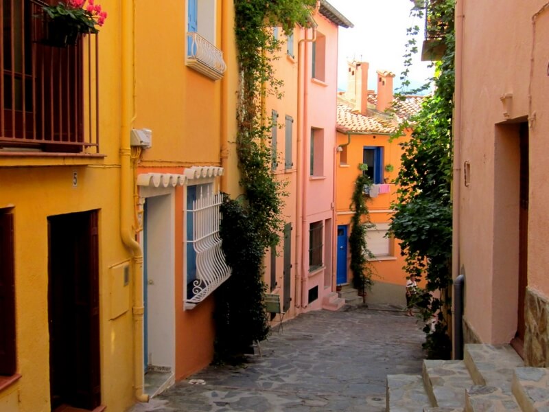 scenic street in collioure, narrow street yellow , orange, and pink buildings