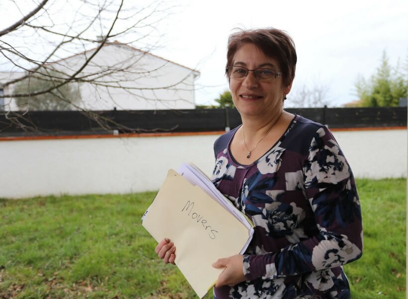 white woman around age 60 holding a folder of paperwork