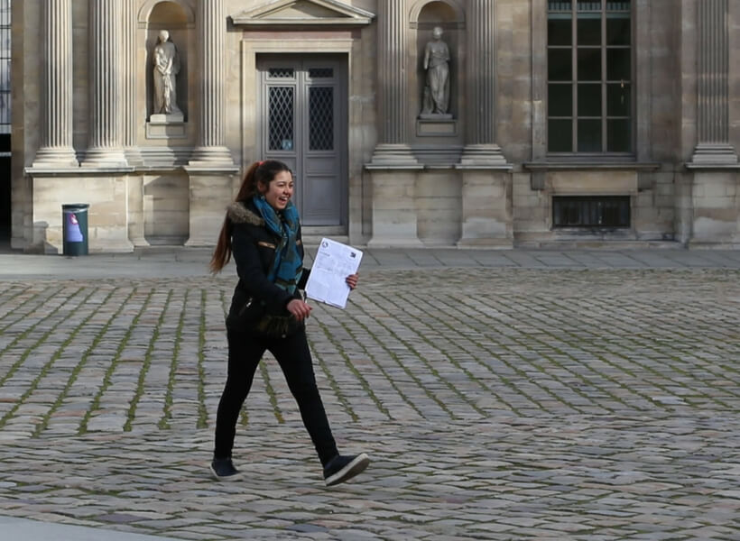 friendly-looking young woman holding a clipboard. She's part of a group of young ladies who try to scam paris visitors every day