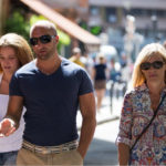 how to look stylish in paris: man wearing a fitted blue v-neck t-shirt, woman wearing a shirt with geometrical patters and a cross body bag