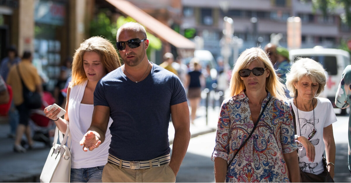 how to look stylish in paris: man wearing a fitted blue v-neck t-shirt, woman wearing a shirt with geometrical patters and a cross body bag