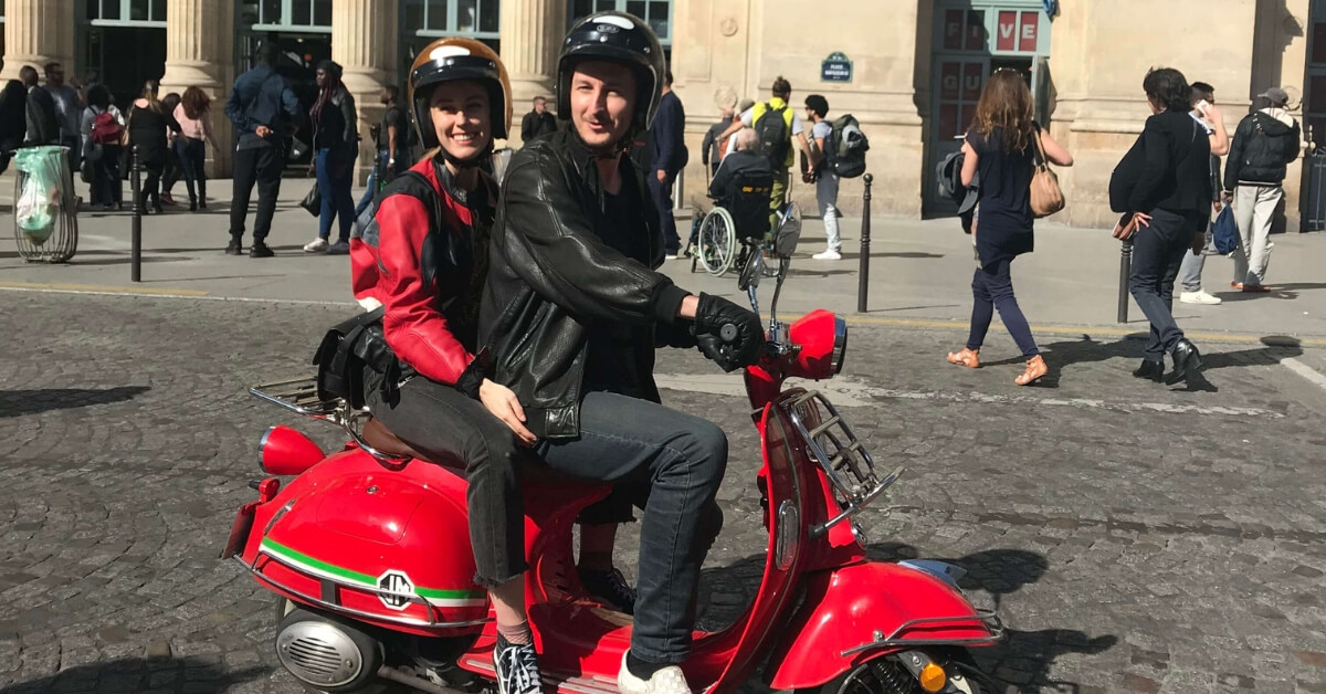 Oliver and his fiancée riding their red scooter in Paris