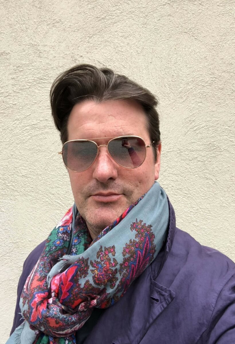 David Palacheck wearing his aviator glasses, his purple sport coat and a colorful scarf