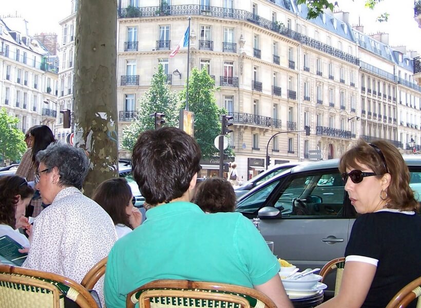 people sitting at a café in Paris with man wearing a bright blue shirt