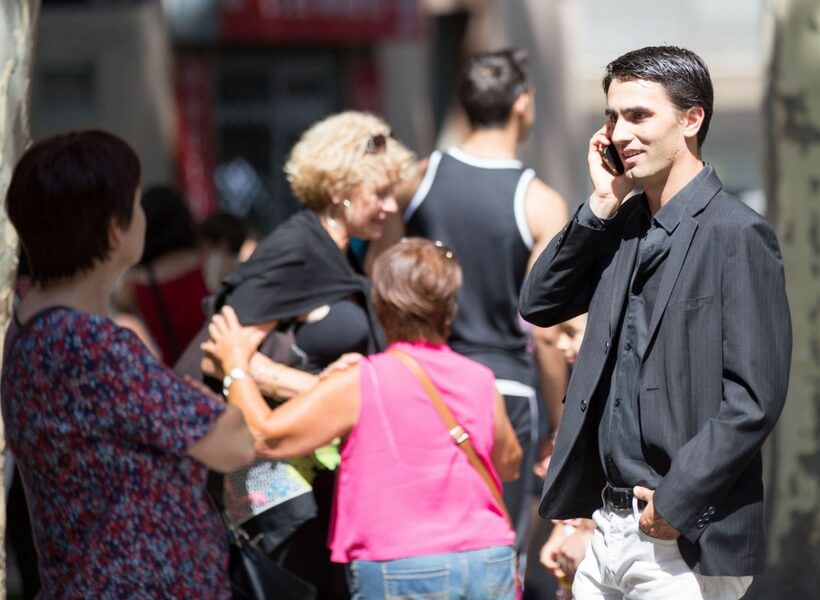 street photography in France: people wearing warm weather attire with man wearing a black shirt and jacket talking on his phone