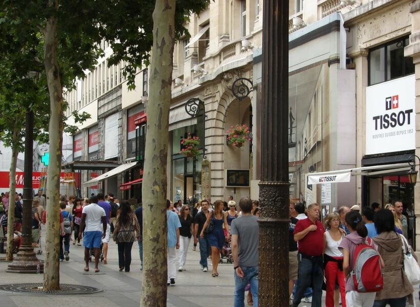 people walking around the Champs Elysées wearing warm weather clothes