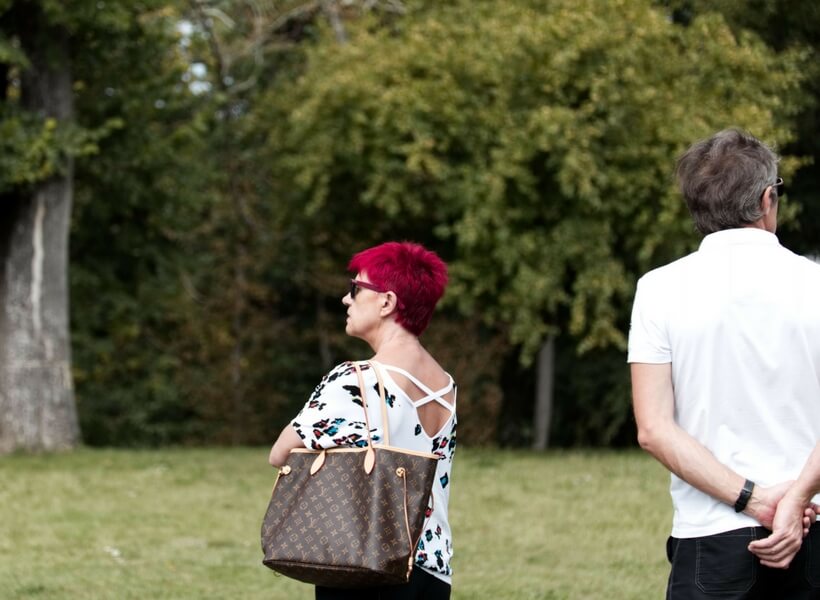 French woman in her early 50s carrying a large fashionable purse and sporting bright burgundy/red hair