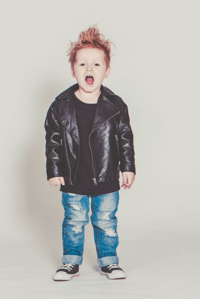 3-year-old boy with spiked red hair wearing holey jeans, a black t-shirt and a perfecto leather jacket