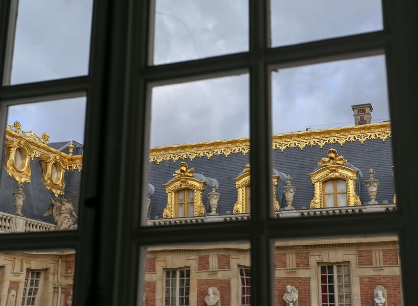 The guilded roof of Versailles seen through a window: day trip to Versailles