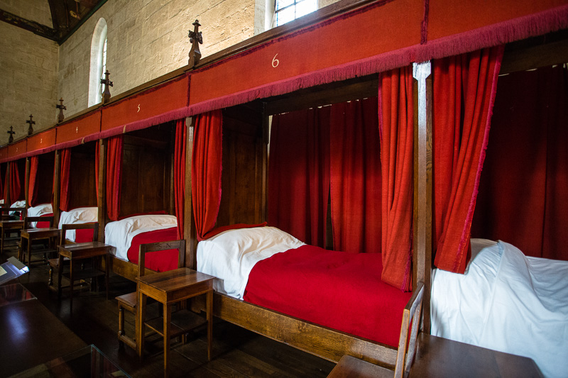 Hospital beds installed in a large room with red drapes for privacy