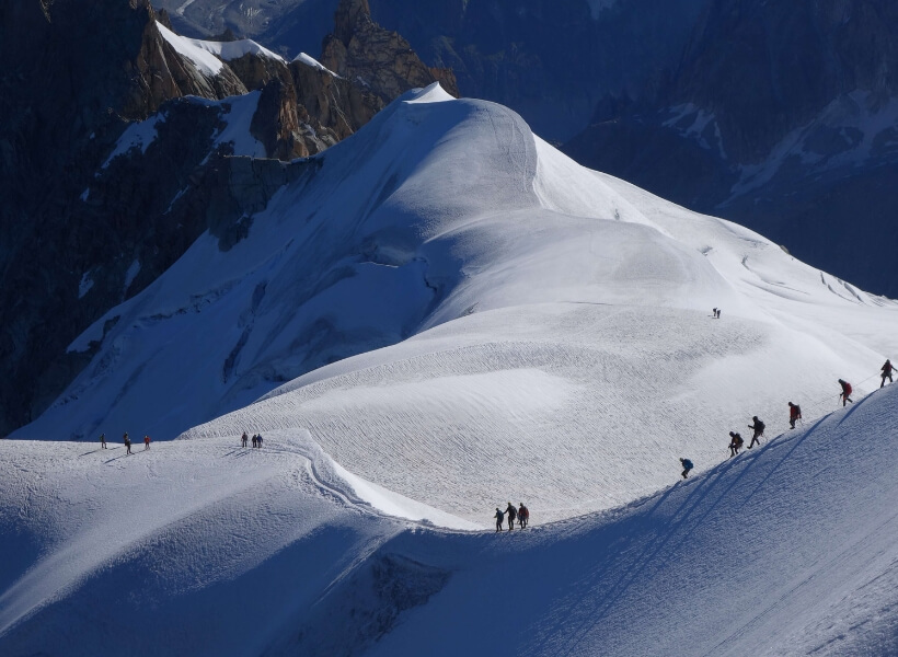 snowy mountain pass with people walking on the crest