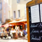 Blackboard menu and restaurant terrasse in the background