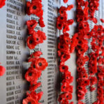 WW1 memorial site covered in garlands of red flowers