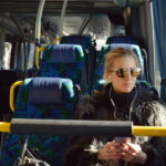 woman on a bus listening to a podcast during her commute to work