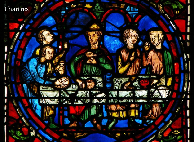 three men and two women sharing a meal around a table covered with food and wine