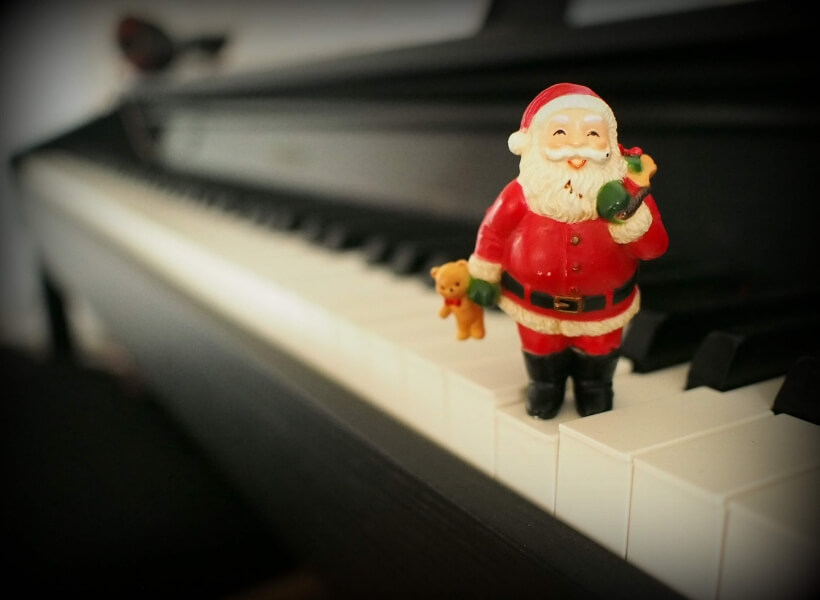 Little Santa statuette standing on a piano keyboard: French Christmas Songs Transcript Episode
