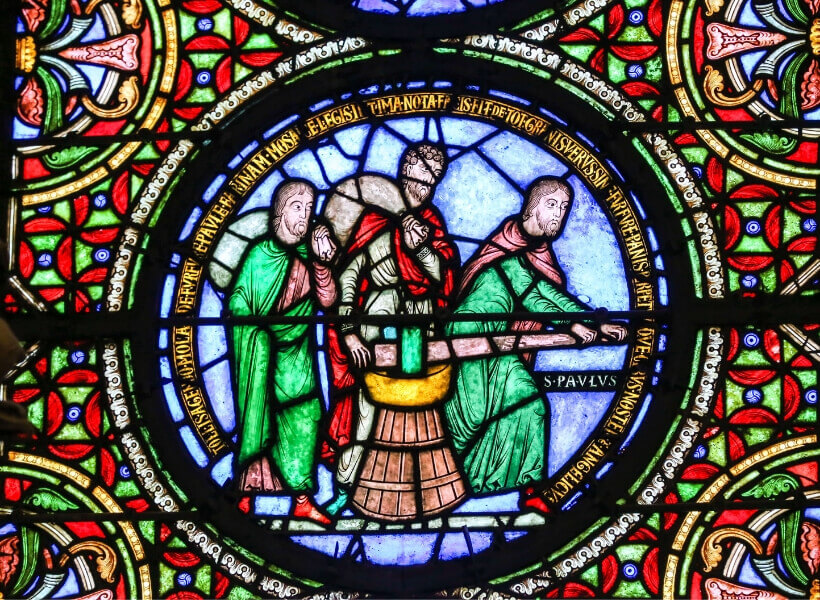 stained-glass window at saint-denis basilica showith two men holding big bags on their backs and a man pushing a piece of lumber 