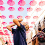 Jessica's son looking up at umbrellas lining a street in France and taking a picture. Great Activities in France for Families with Children episode.