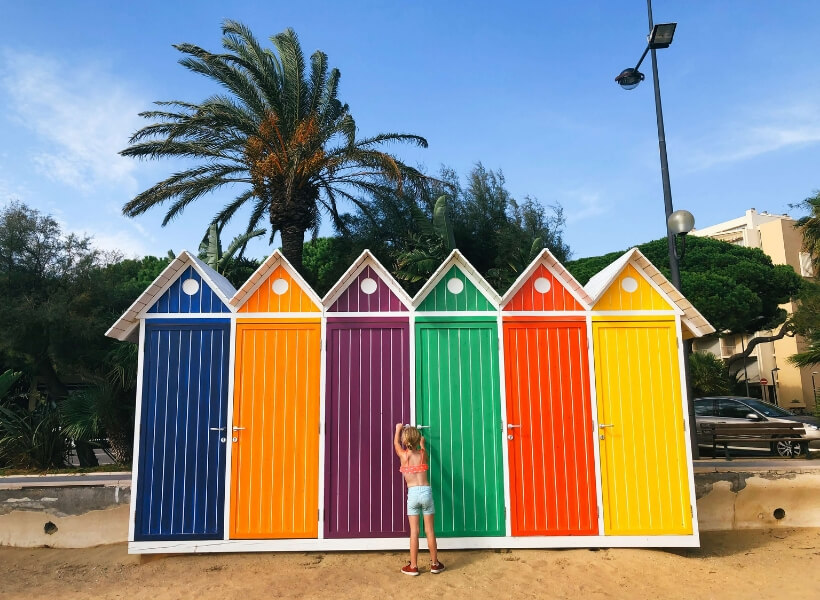 Girl standing in front of colorful changing rooms on a French beach: vacation photos