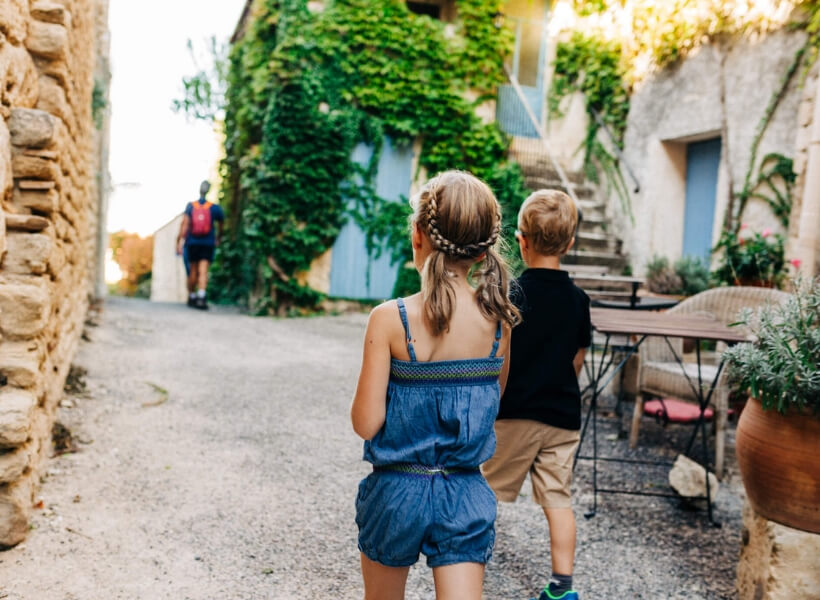 we see the back of a boy and a girl walking in a scenic street in France: vacation photos episode