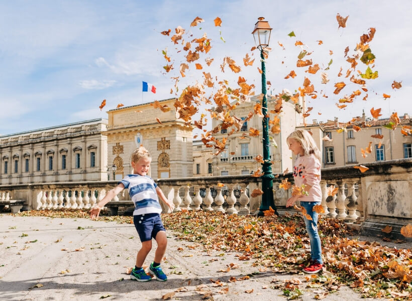 Boy and girl playing with dead leaves in the Tuileries garden: vacation photos episode