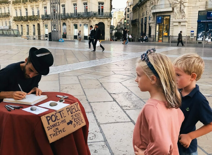 children talking to a street poet who is writing them a poem as they watch: Great Destinations in France for Families episode 