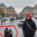 Eric's wife posing in front of the Paris Opera with scammers working in the background