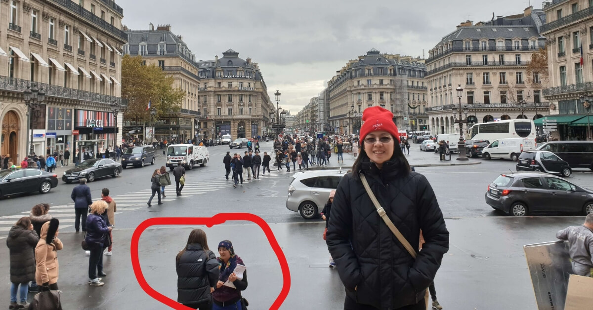 Eric's wife posing in front of the Paris Opera with scammers working in the background