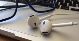 Laptop, glasses and earbuds on a table