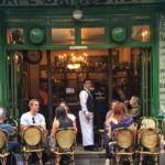 Café in Paris with people sitting outside and waiter looking at the camera