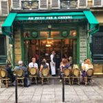 Café in Paris with people sitting outside and waiter looking at the camera
